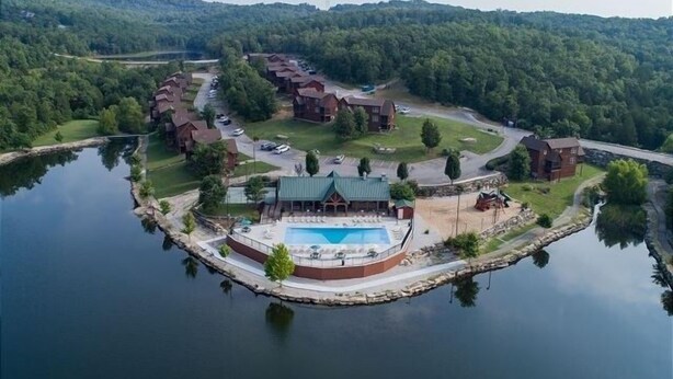 A lakeside resort with multiple cabins, a central building with a pool, and a surrounding wooded area. - Heavenly Hideaway 2 Bedroom Condo by RedAwning (Branson West)