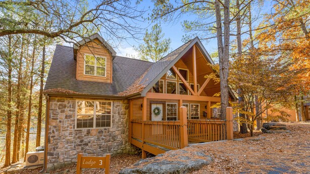 A lodge with a stone facade, wooden deck, and a sign indicating 'Lodge 3'.
