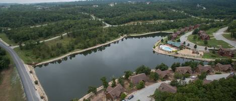 An aerial view of a residential area with a large lake, houses, and a swimming pool.