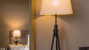 A modern hotel room with a standing floor lamp, a round table, and a bed with a headboard.