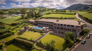 A large, modern hotel with a swimming pool, surrounded by lush green fields and mountains. - The Lince Nordeste (Nordeste)