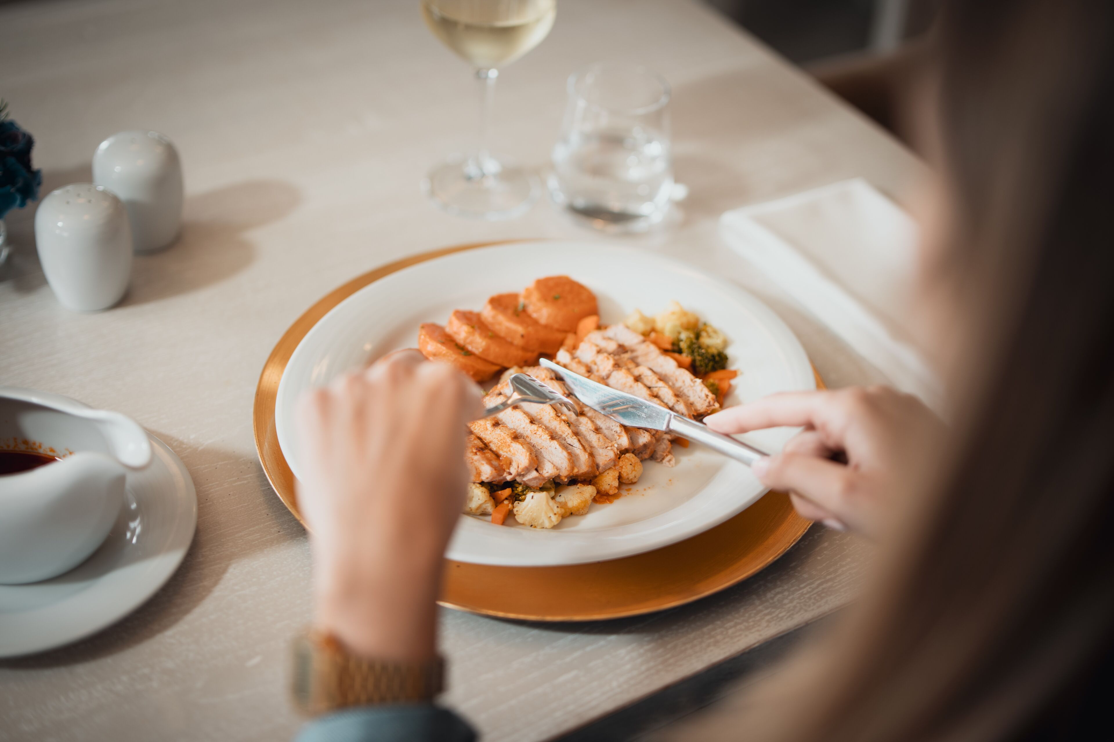 Una mesa de comedor con un plato de comida, un vaso de agua y una taza de café.