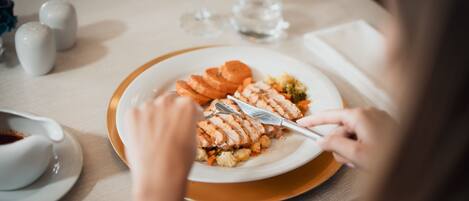 A dining table with a plate of food, a glass of water, and a cup of coffee.