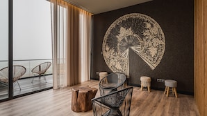 A modern room with a large window, two wicker chairs, a round wooden table, and a unique wall mural. - The Lince Nordeste (Nordeste)