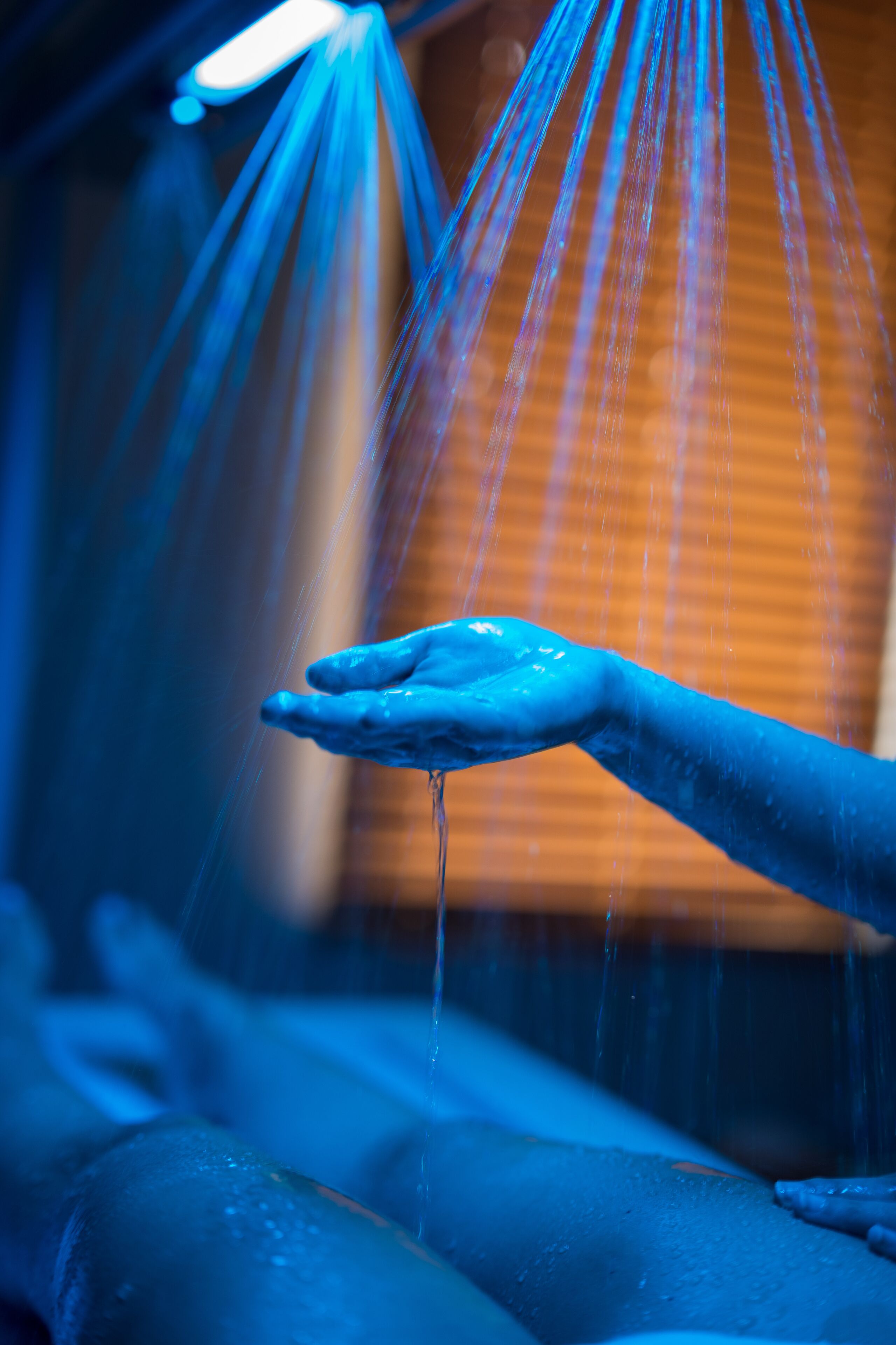 A hand under a water feature with streams of water flowing down.