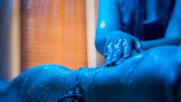 A person receiving a massage with water droplets visible on their skin.