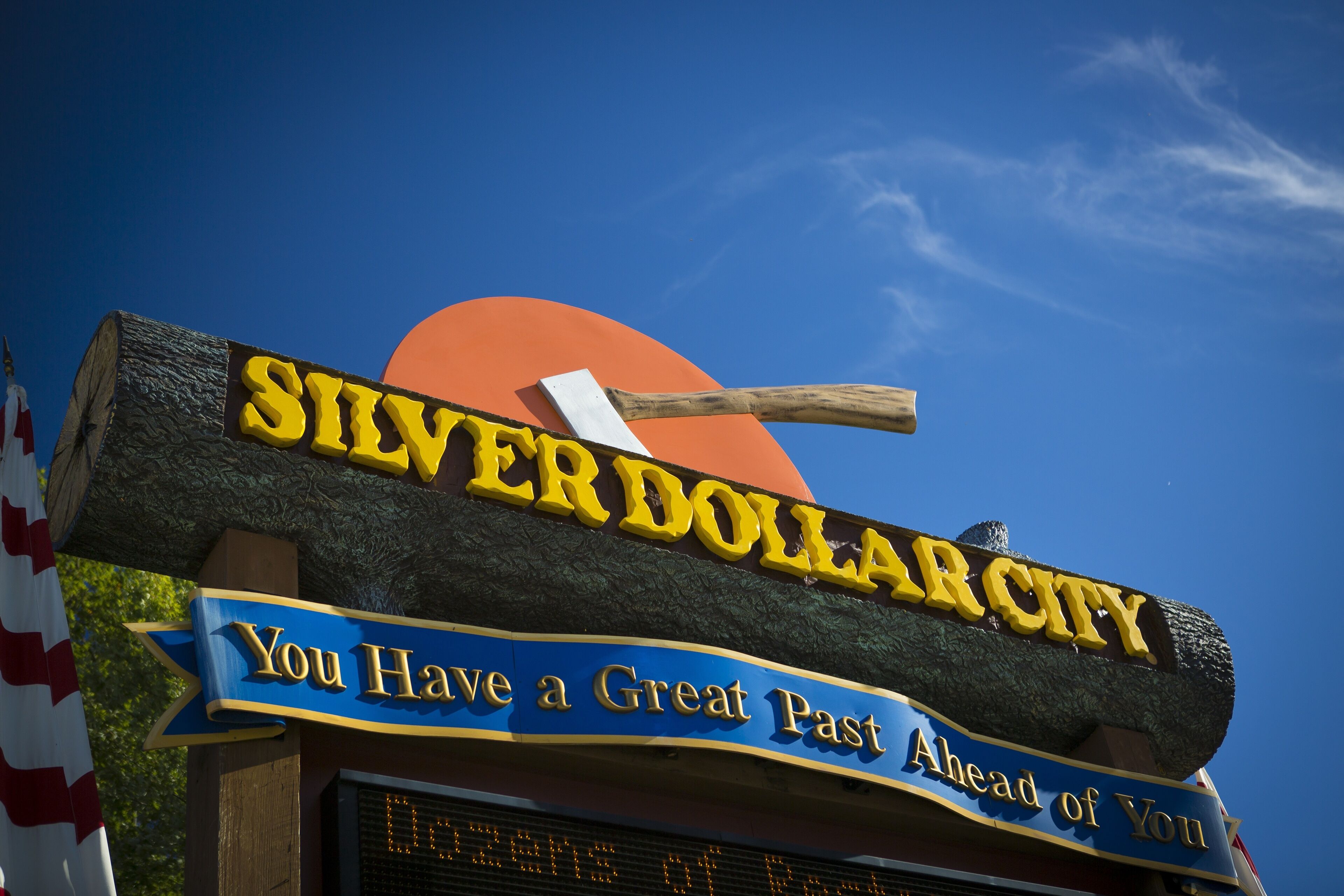 A sign with the text "SILVERDOLLAR CITY" and "You Have a Great Past Ahead of You" against a clear blue sky.