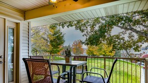 A covered patio with a table and chairs, overlooking a well-maintained lawn and trees. - View at the Foothills by RedAwning (Branson)