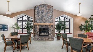 A spacious room with a stone fireplace, large windows, and a dining area with wooden chairs. - View at the Foothills by RedAwning (Branson)