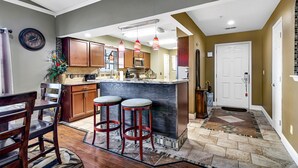 A modern kitchen with wooden cabinets, a marble island, and red bar stools. - View at the Foothills by RedAwning (Branson)