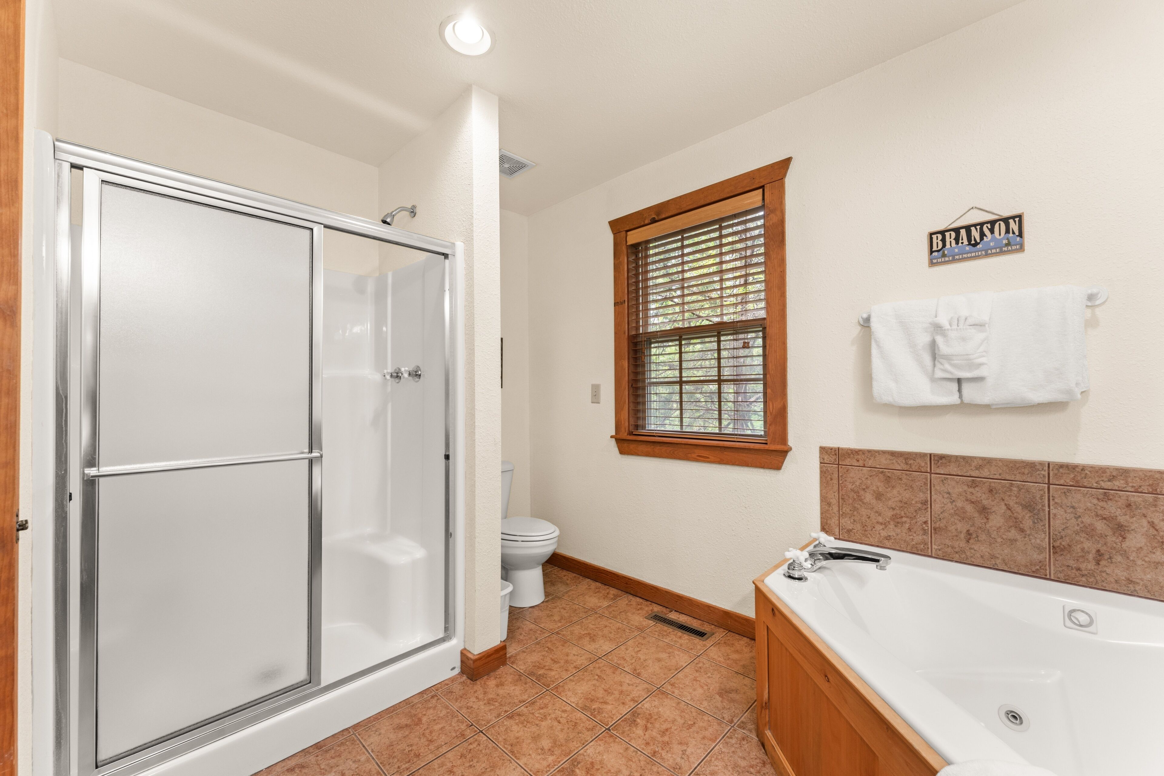Un baño con cabina de ducha, inodoro, ventana y bañera.