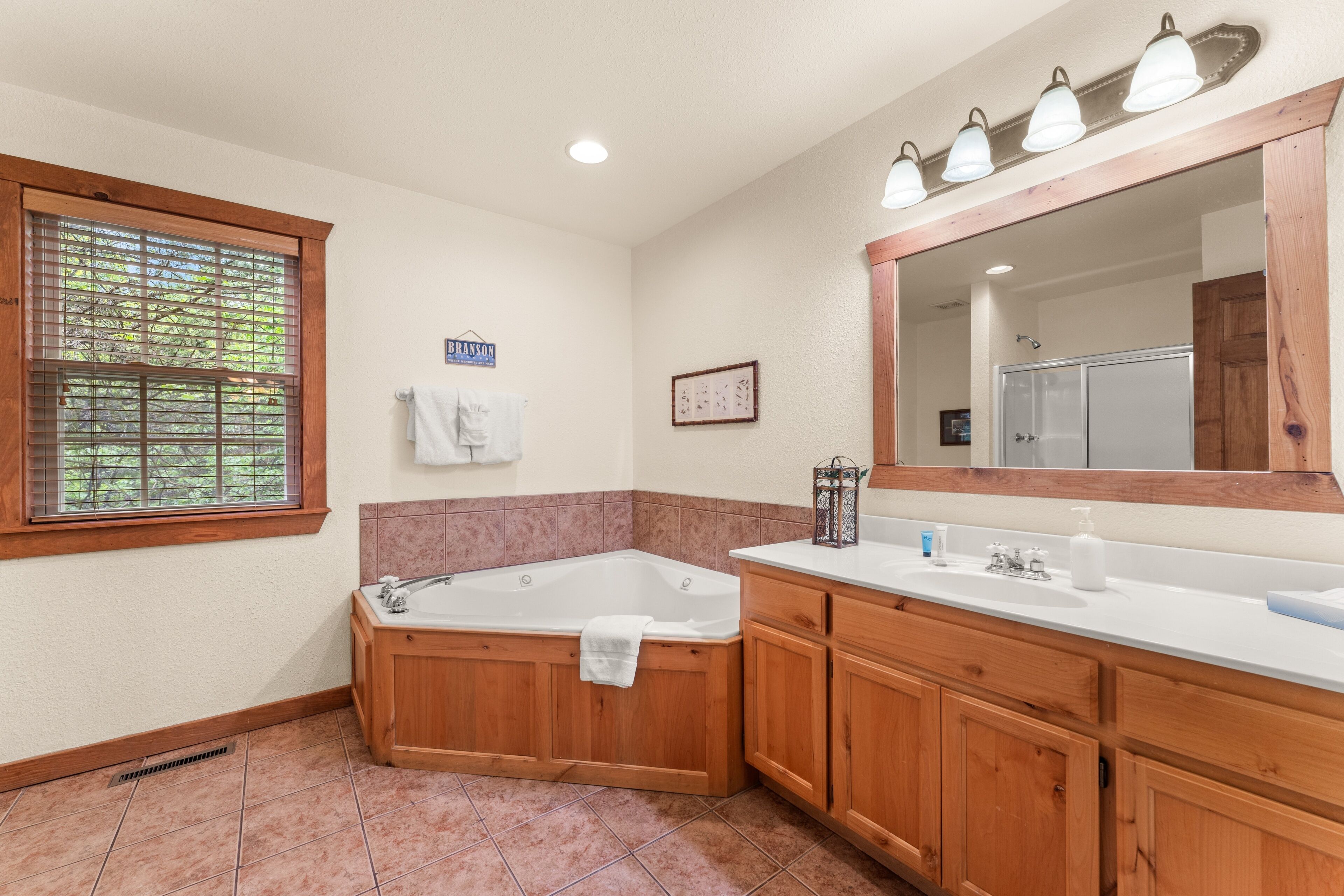 A bathroom with a bathtub, vanity, and a large mirror.