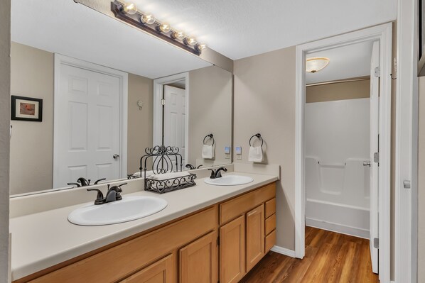 A bathroom with two sinks, a large mirror, and a vanity with wooden cabinets.