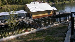 Un edificio lungo il fiume con tetto in metallo, un molo e una ringhiera metallica a riva.