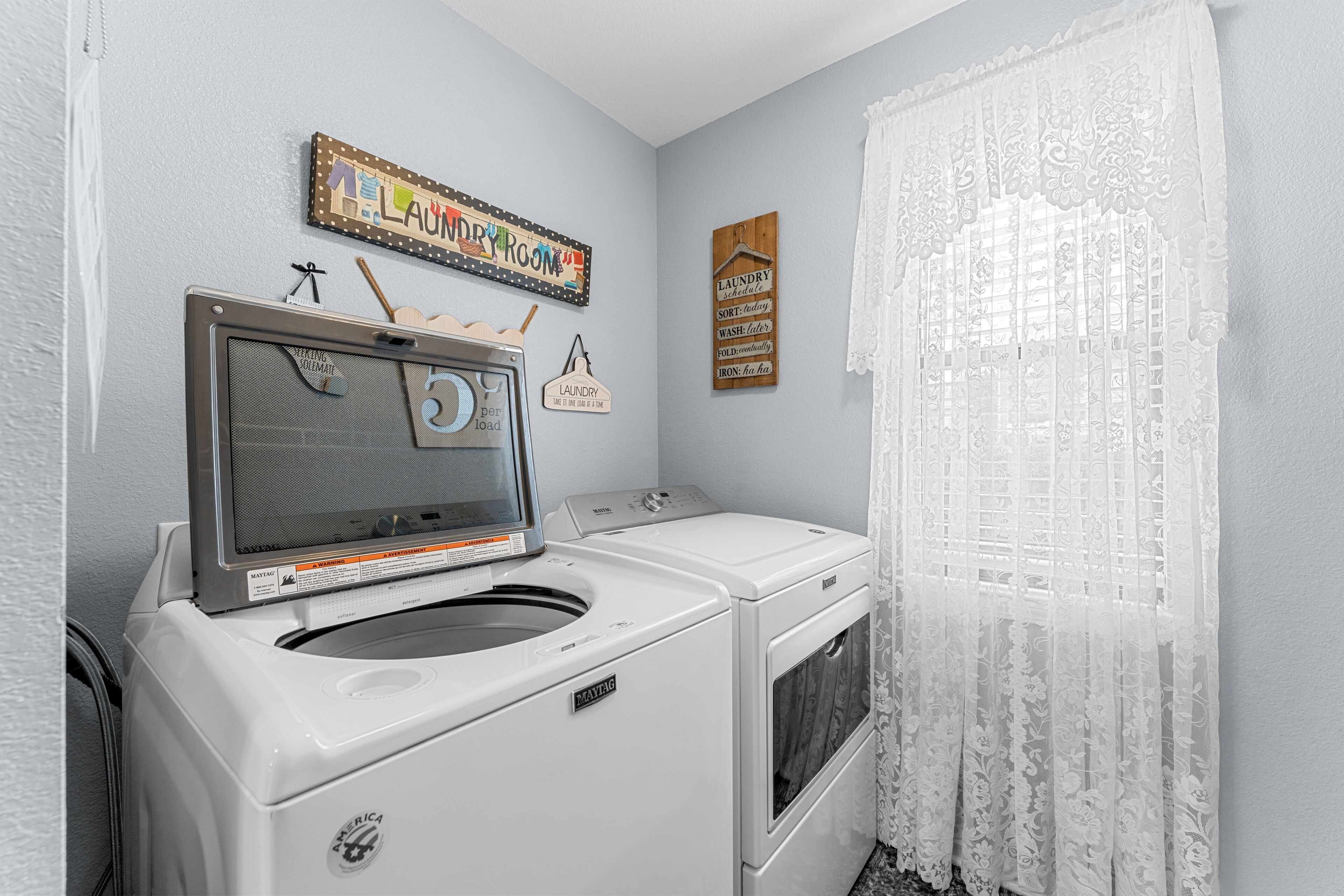 A laundry room with a washing machine, dryer, and a sign that reads 'Laundry Room.'