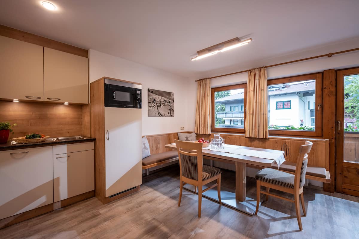 Una cocina moderna con armarios de madera, un microondas y una zona de comedor con banco y sillas.