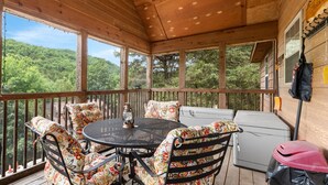 A covered outdoor deck with a round table, chairs, and a lantern. - Dakota Lodge 2 Bedroom Home by RedAwning (Branson West)