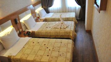 A hotel room with two beds, each with a floral bedspread and a decorative towel. There are bedside tables with lamps and a clock.