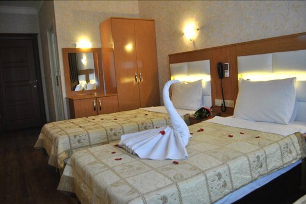 A hotel room with two beds, a wooden wardrobe, a mirror, and a telephone.