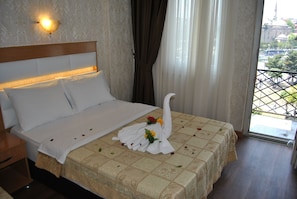A hotel room with a bed, a nightstand, a window with curtains, and a view of a building outside. - Hotel Star Park (Istanbul)