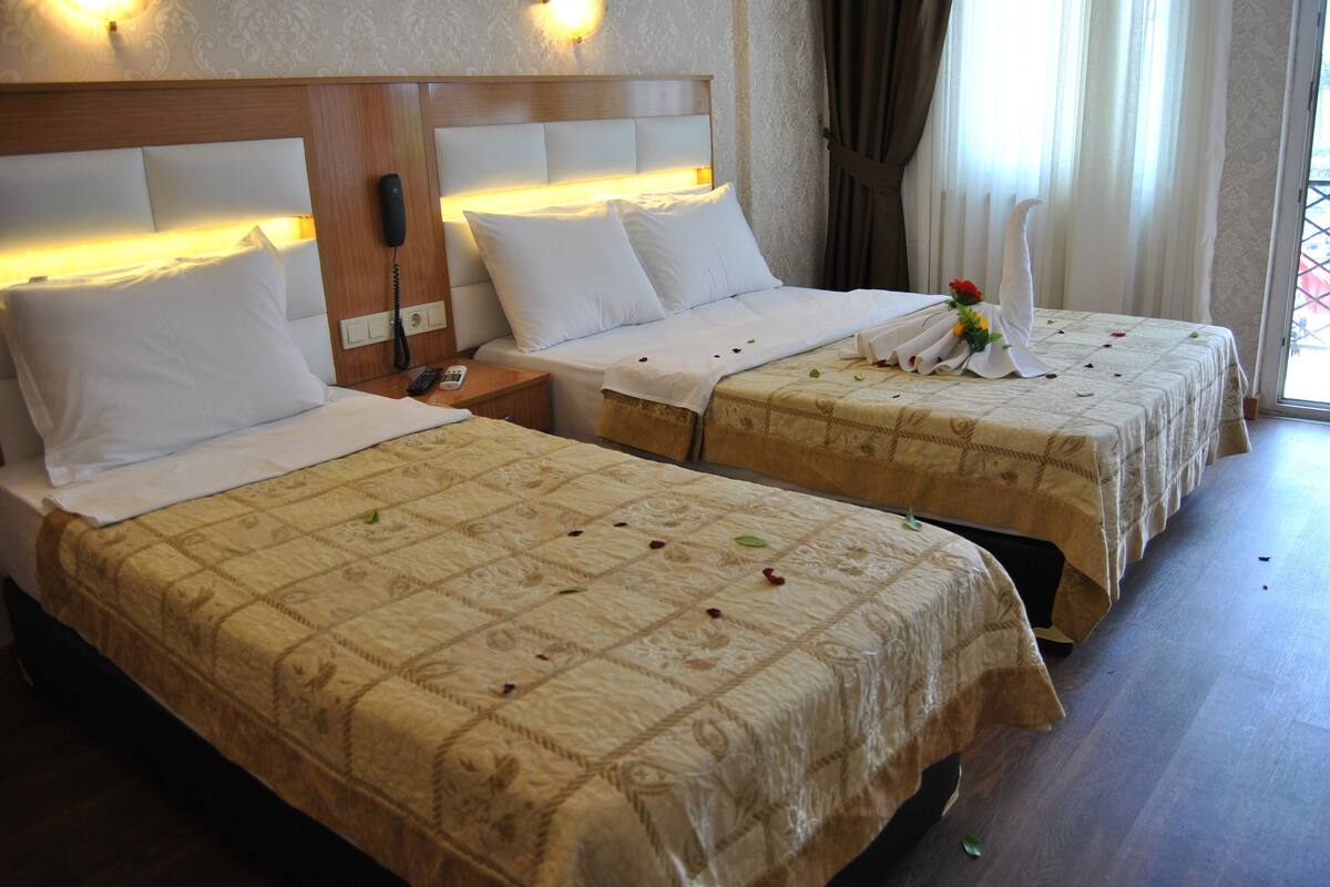 Two double beds with headboards, bedside tables, and a telephone.