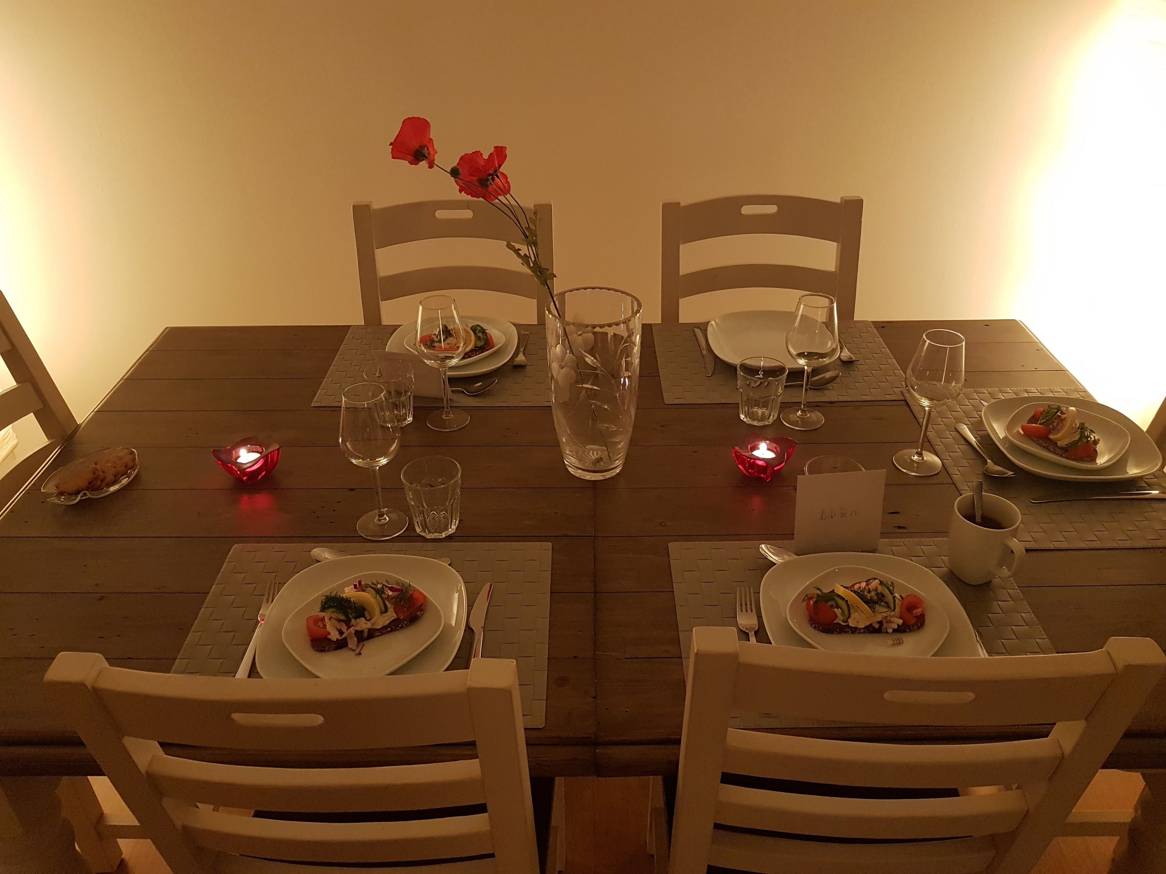A dining table set with plates, cutlery, glasses, and candles.