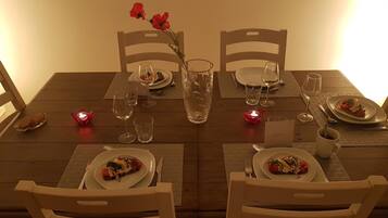 A dining table set with plates, cutlery, glasses, and candles.