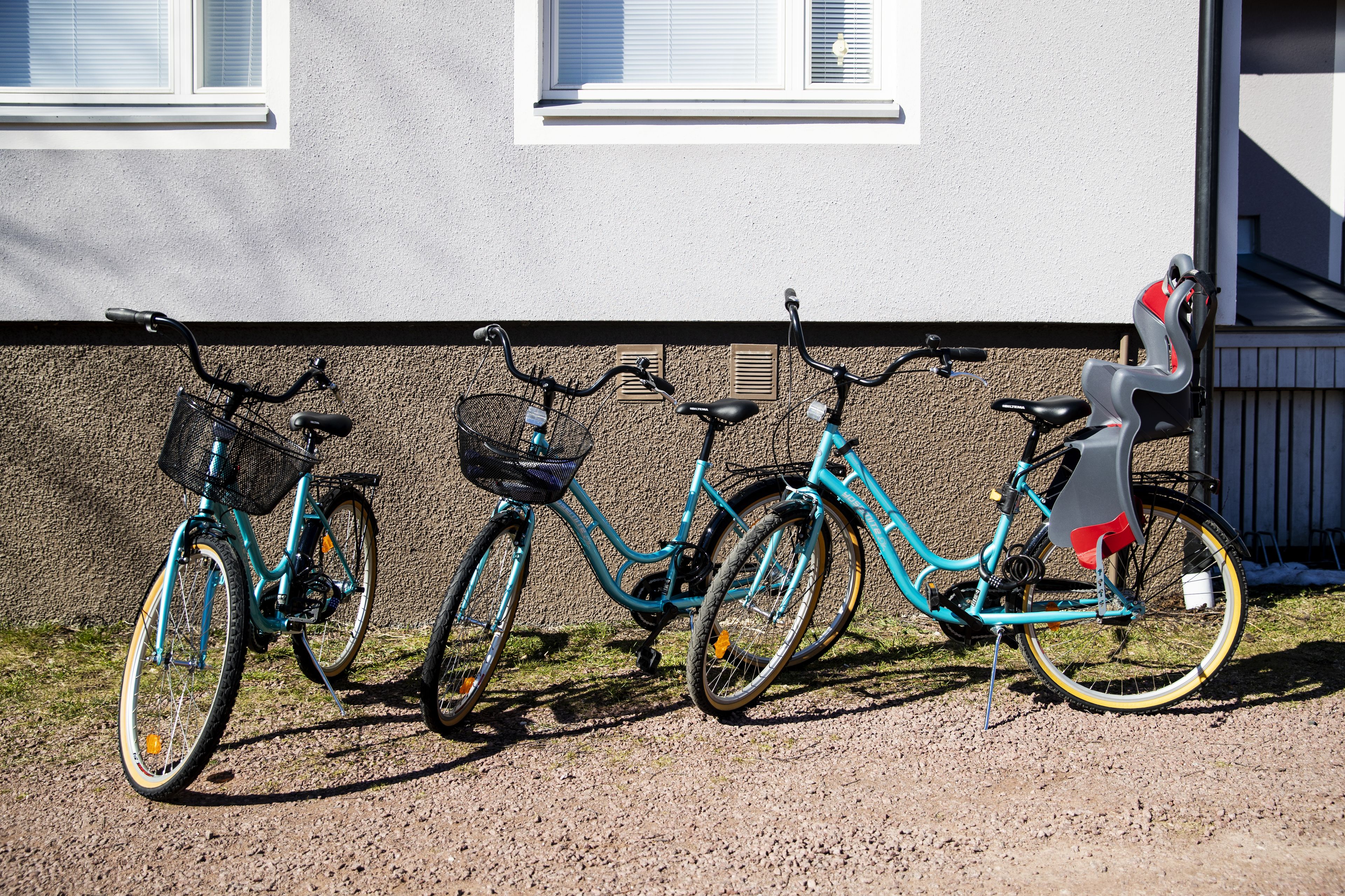 Three bicycles parked against a building wall.