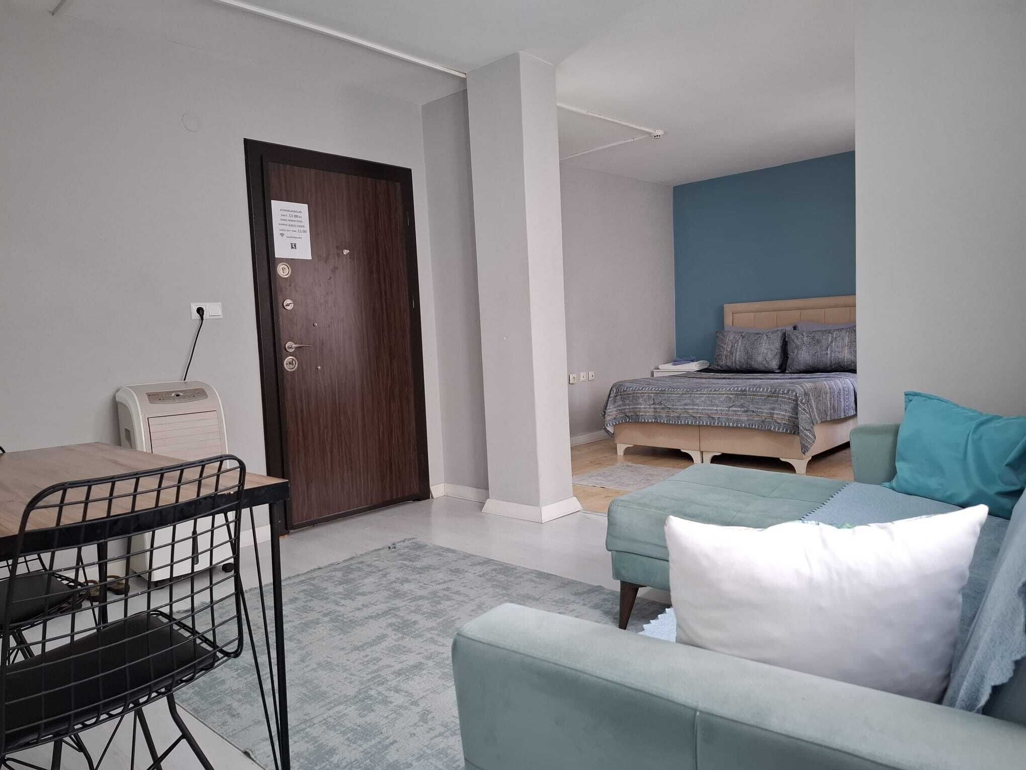 Een kleine kamer met een bed, een slaapbank, een tafeltje en een stoel.