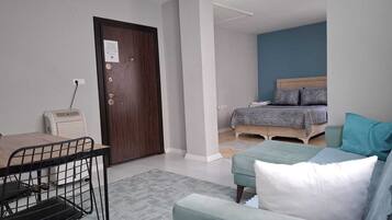 Een kleine kamer met een bed, een slaapbank, een tafeltje en een stoel.