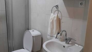 A bathroom with a toilet, sink, and shower.