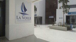 Moderni rakennus, jossa on kyltti, jossa lukee ”LA VOILE RESTAURANT”, ja toinen kyltti, jossa lukee ”ACCUWEI”.