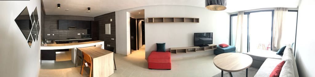 A modern living space with a kitchen, dining area, and a seating area with a TV.