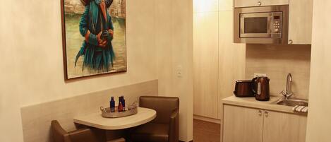Habitación de hotel compacta con comedor, microondas y lavamanos.