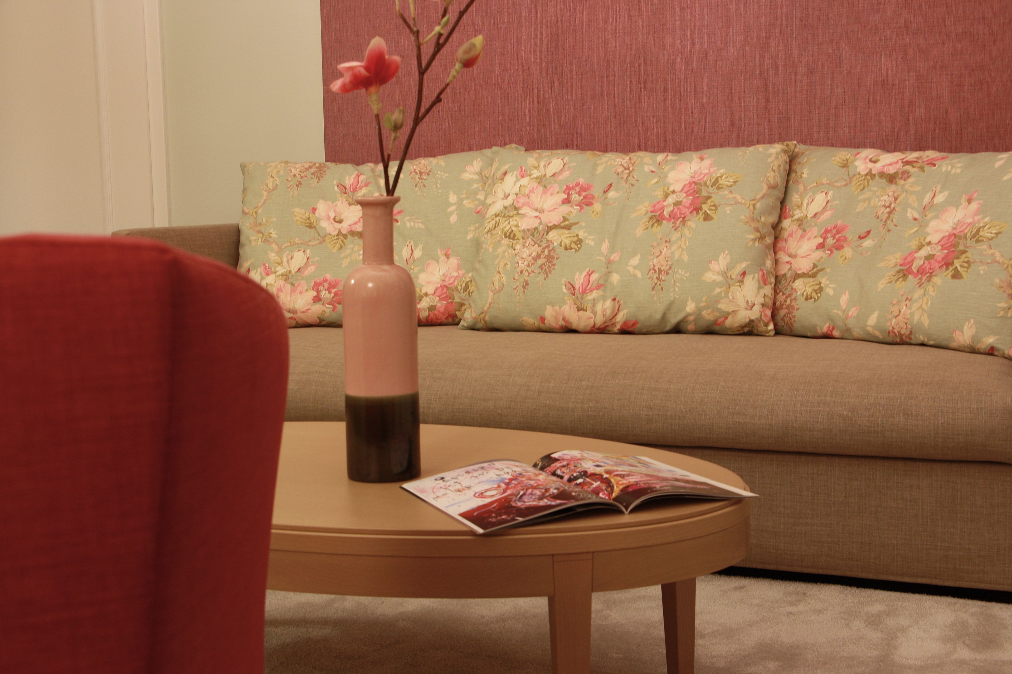 Un salon avec un canapé, une table, un vase et un magazine.