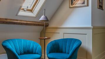 Een kamer met twee blauwe stoelen, een vloerlamp en een dakraam.
