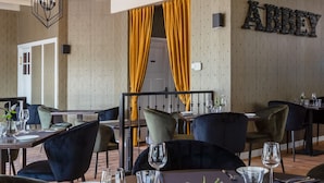 A restaurant interior with tables set for dining, a bar area, and a wall with the word "Abbey". - Abbey Abcoude (Abcoude)