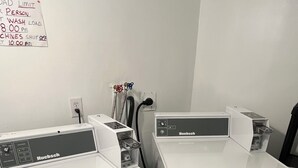 Two white Huebsch brand washing machines in a laundry room with a sign on the wall indicating a person wash load limit and a 10:00 pm machines shut off time. - City Hostel-HI-ST.JOHN'S (St. John's)