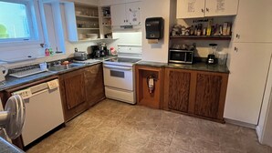 A compact kitchen with white cabinets, a built-in oven, a microwave, and a dishwasher. - City Hostel-HI-ST.JOHN'S (St. John's)
