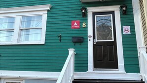 A green building with a black door, white trim, and a red 'Hi Canada' sign. - City Hostel-HI-ST.JOHN'S (St. John's)