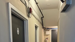 A hallway with wooden flooring, a fire alarm, and a door with a sign. - City Hostel-HI-ST.JOHN'S (St. John's)