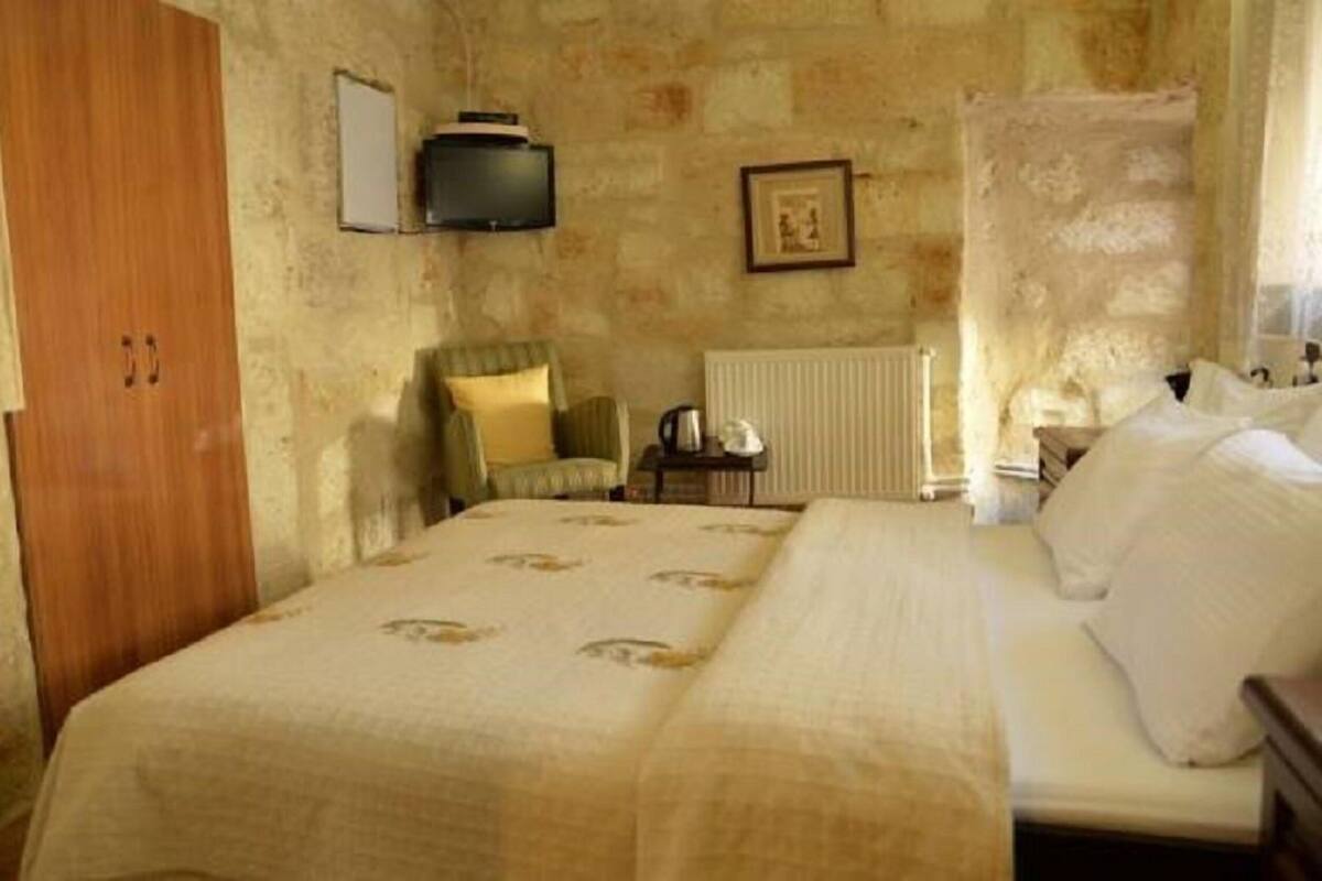 A bedroom with a bed, a chair, a radiator, and a television on the wall.