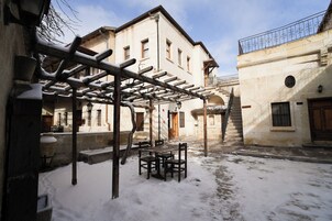 Un patio cubierto de nieve con una pérgola de madera y una mesa con sillas.