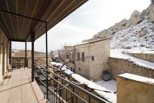 Un balcón con vistas a un patio cubierto de nieve y un edificio de piedra.