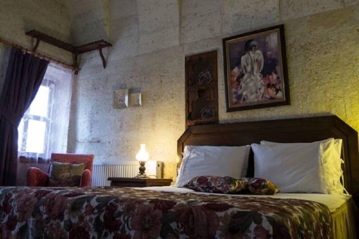 A room with a bed, a nightstand, a lamp, a chair, and a painting on the wall.