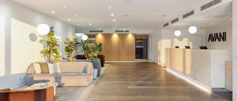 A modern reception area with a wooden reception desk, seating area with sofas, and potted plants.