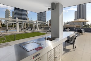 Un área de cocina al aire libre con pileta, estación de parrilla y asientos.