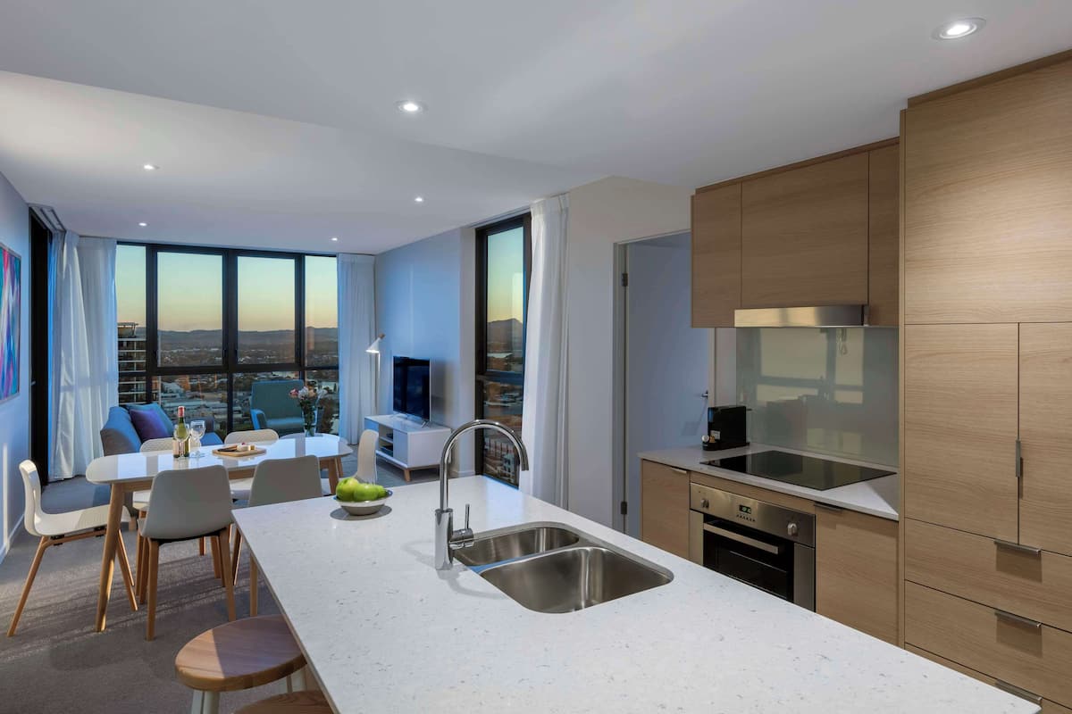 A modern kitchen with a large island, stainless steel appliances, and a view of the city.
