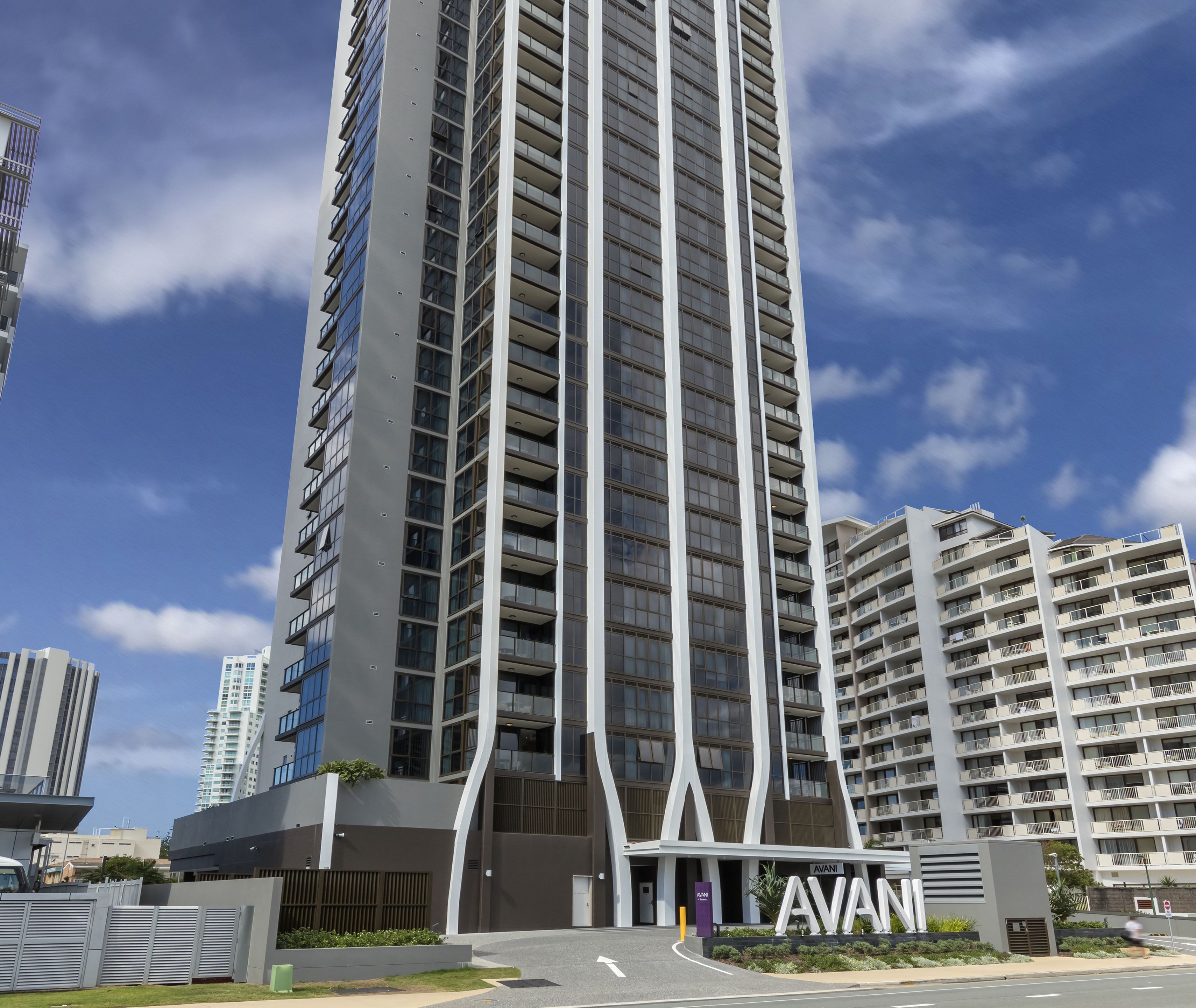 Un edificio de gran altura con un diseño arquitectónico moderno, que presenta una entrada destacada con el nombre 'AVANI'.