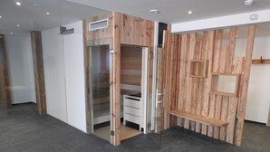 A modern room with a wooden accent wall, a glass door closet, and a tiled floor. - Hotel Moawirt (Wagrain)